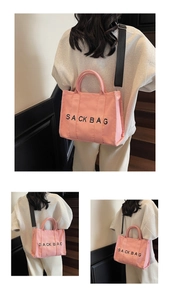 Pink canvas sack bag detail showing detachable black strap and elegant printed text