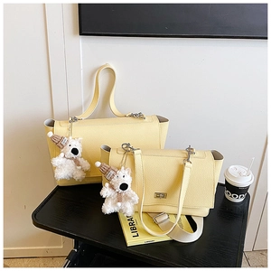 Detailed view of yellow litchi pattern leather handbags with a cute white plush bear pendant