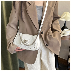 Detail showing white crocodile embossed handbag with heart metal buckle and chain decoration