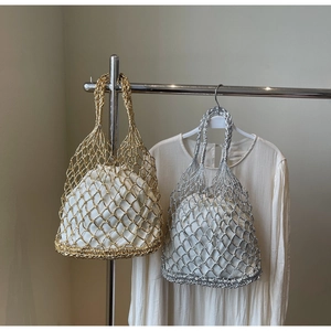 Detail of hollow woven mesh beach bags in gold and silver with white drawstring liners