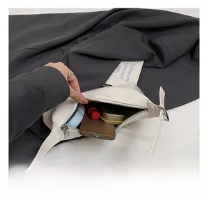 Gros plan sur l'intérieur spacieux de ce sac hobo blanc contenant téléphone et cosmétiques