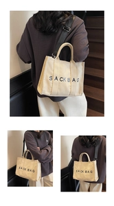 Detail of canvas sack bag showing the adjustable black nylon shoulder strap and metal hooks