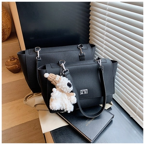 Detail of black lychee grain leather business totes with silver twist locks and teddy charm