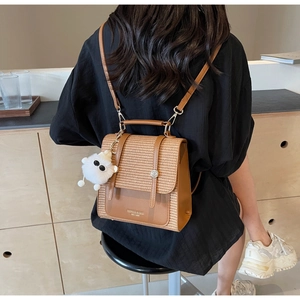 Detailed view of brown textured weaving backpack with plush charm in a lifestyle setting