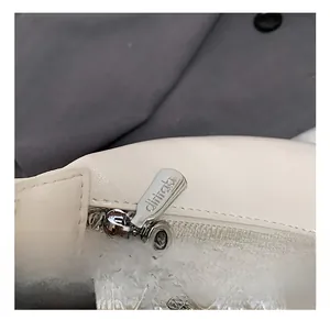 Détail du sac à main crème avec breloque en perles et fermeture éclair en métal argenté