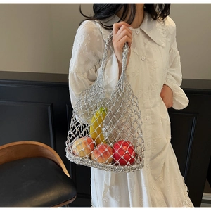 Detail of silver metallic woven hollow net tote bag filled with fresh fruits in hand