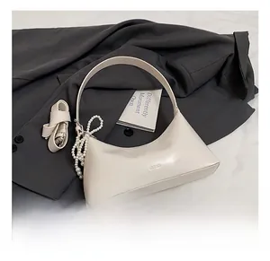 Vue de dessus d'un sac demi-lune crème avec chaîne perles et bandoulière sur veste