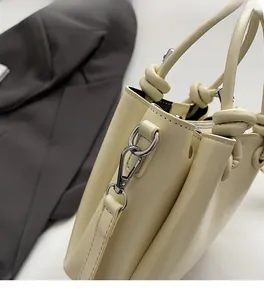 Détail du sac seau jaune crème avec poignée à nœud unique et finitions métalliques argentées