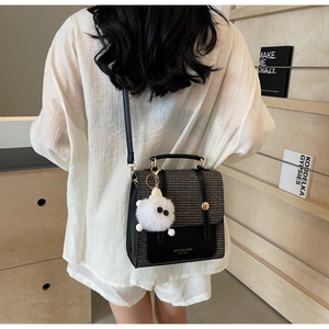 Detail of elegant two-tone leather handbag with metallic lock and plush pendant accessory