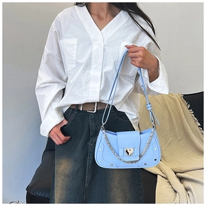 Close-up of light blue croc-effect bag with silver heart buckle on shoulder