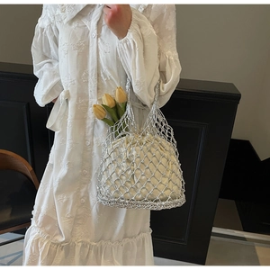 Close-up of silver hollow woven mesh tote bag with white drawstring inner pouch and flowers