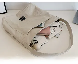Spacious interior of beige pleated tote bag showing phone, wallet, notebook and umbrella