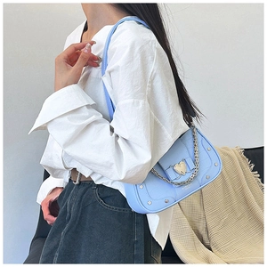 Detail view of light blue crocodile texture bag with silver chain and heart buckle