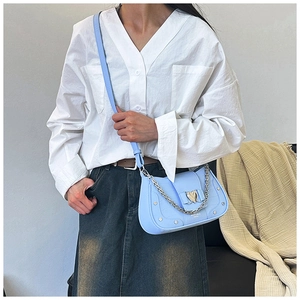 Detail of light blue faux leather bag with stone pattern, heart buckle and silver chain