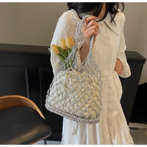 Detail view of woven silver mesh tote bag with a cream drawstring pouch and tulip decor