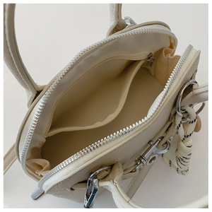 Top view of cream shell bag showing spacious interior with zipper pocket and leather texture