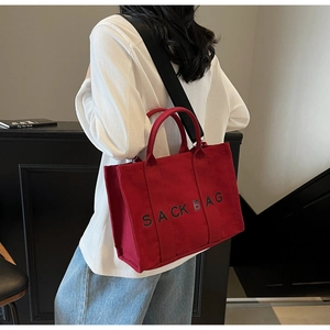 Detail view of large red canvas tote bag with black SACK BAG text and adjustable strap