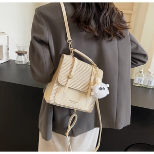 Detail of woven straw and leather beige crossbody bag with adjustable strap and plush charm