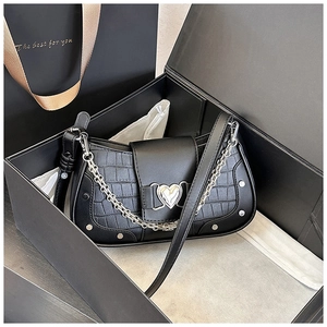 Detail of black faux crocodile leather bag with silver heart lock and metal chain