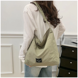 Detail of olive green large tote bag with brand label on textured fabric surface