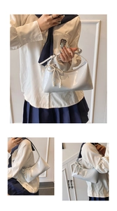 Détail du sac baguette en cuir verni bleu clair avec pendentif nœud en perles et logo