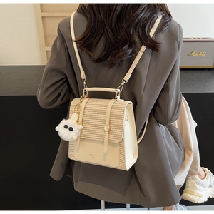 Detail of a beige woven backpack with gold metal buckles and a white plush charm