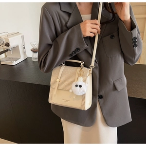 Detail view of woven leather crossbody bag held by a model wearing a dark grey suit