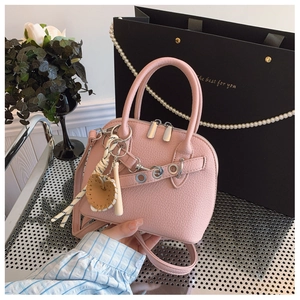 Detailed macro of pink lychee leather shell bag with unique baseball charm and metal studs