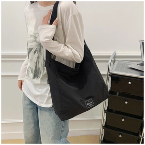 Detail of black canvas tote bag showing the textured fabric and brand metal tag