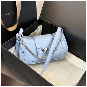 Detail of light blue stone-embossed bag with silver heart buckle and metal chain in gift box