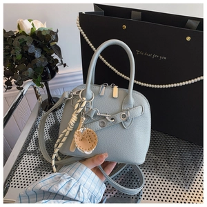 Detail view of light blue lychee texture shell bag with creative woven pendant and metal buckle