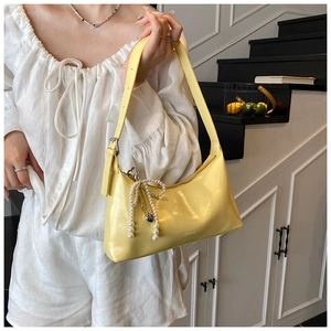 Détail du sac sous l'aisselle en cuir jaune avec breloque cœur perle et logo embossé