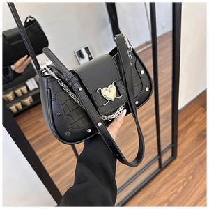 Detail of black faux leather underarm bag with crocodile texture and heart buckle