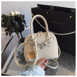 Detail of cream shell bag with lychee pattern leather and baseball charm accessory