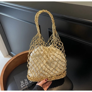 Detailed shot of golden mesh woven handbag with white drawstring pouch on a leather surface