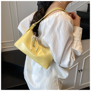 Détail du sac hobo en cuir souple jaune vif avec nœud en perles et pendentif cœur