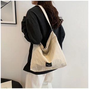 Detail view of large cream tote bag with stylish pleated texture and wide shoulder strap