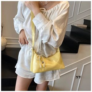 Vue détaillée du sac sous le bras en cuir jaune souple avec pendentif nœud en perle