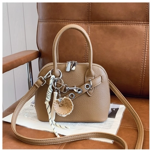 Detailed macro view of camel shell bag texture with leather strap and heart charm
