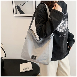 Detail of the minimalist light grey large capacity canvas tote bag with black square brand tag