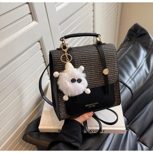 Detail of woven fabric and leather backpack with a cute white plush monster keychain