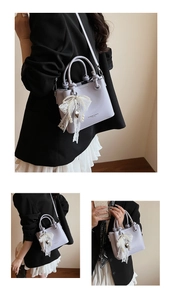 Détail du sac seau lavande avec nœud en dentelle blanche et pendentif perle