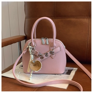 Pink lychee texture shell bag with silver dual zippers and baseball bat charm on leather seat