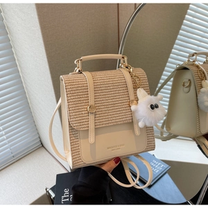 Close-up of the woven texture lid and metal buckle on the cream-colored square backpack