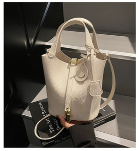 Detail of white lychee leather bucket bag with gold lock and smiling charm