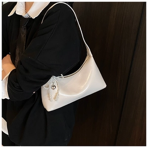 Détail latéral d'un sac demi-lune blanc en simili cuir avec chaîne en perles et cœur