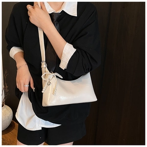Détail du sac blanc brillant avec nœud en perles et pendentif cœur sur la bandoulière