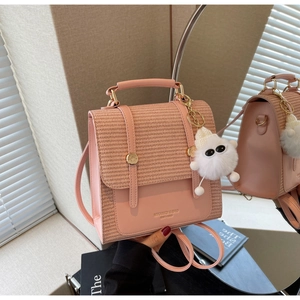 Detail of pink woven backpack with gold buckles and a cute white plush doll charm