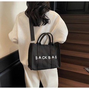 Detailed back view of a black canvas SACK BAG tote with white letters and strap