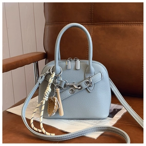 Detail of light blue shell bag in pebble leather with creative decorative pendant